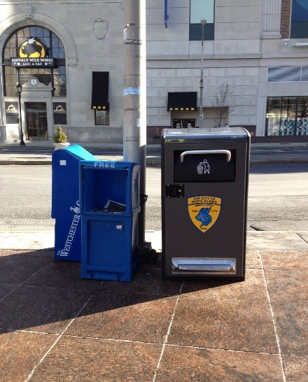 Two garbage cans on a city sidewalk