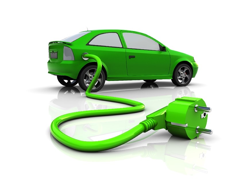 A green car with an electrical cord coming out of it